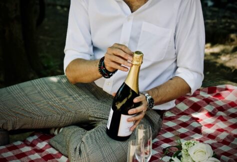 Magnolia - Meditation & Achtsamkeit - Meditationspicknick - ein Mann öffnet gerade eine Sektflasche