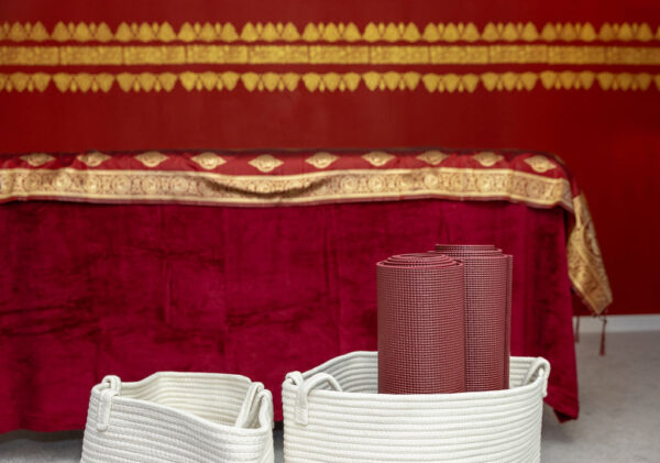 Magnolia - Meditation und Achtsamkeit - dunkelrote, eingerollte Yogamatten in einem Korb