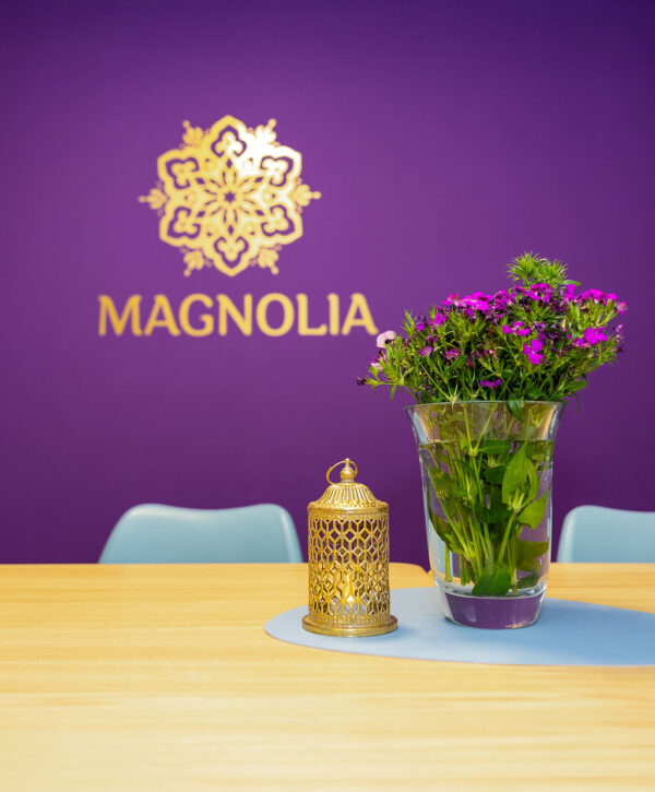 Magnolia, Meditation & Achtsamkeit, Julia Mauroschek - Blumen in einer Vase auf einem Tisch vorm Magnolia-Logo