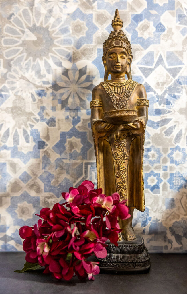 Magnolia, Meditation & Achtsamkeit, Julia Mauroschek - rote Bluemen zu Füßen einer asiatischen Statue