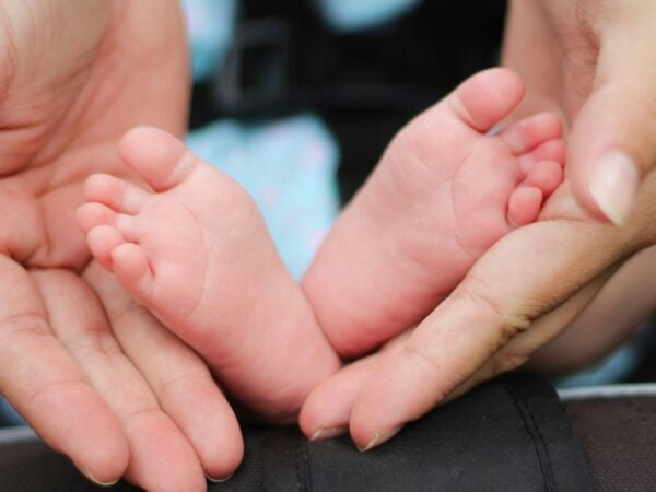Zwei Hände halten zwei kleine Baby Füße.