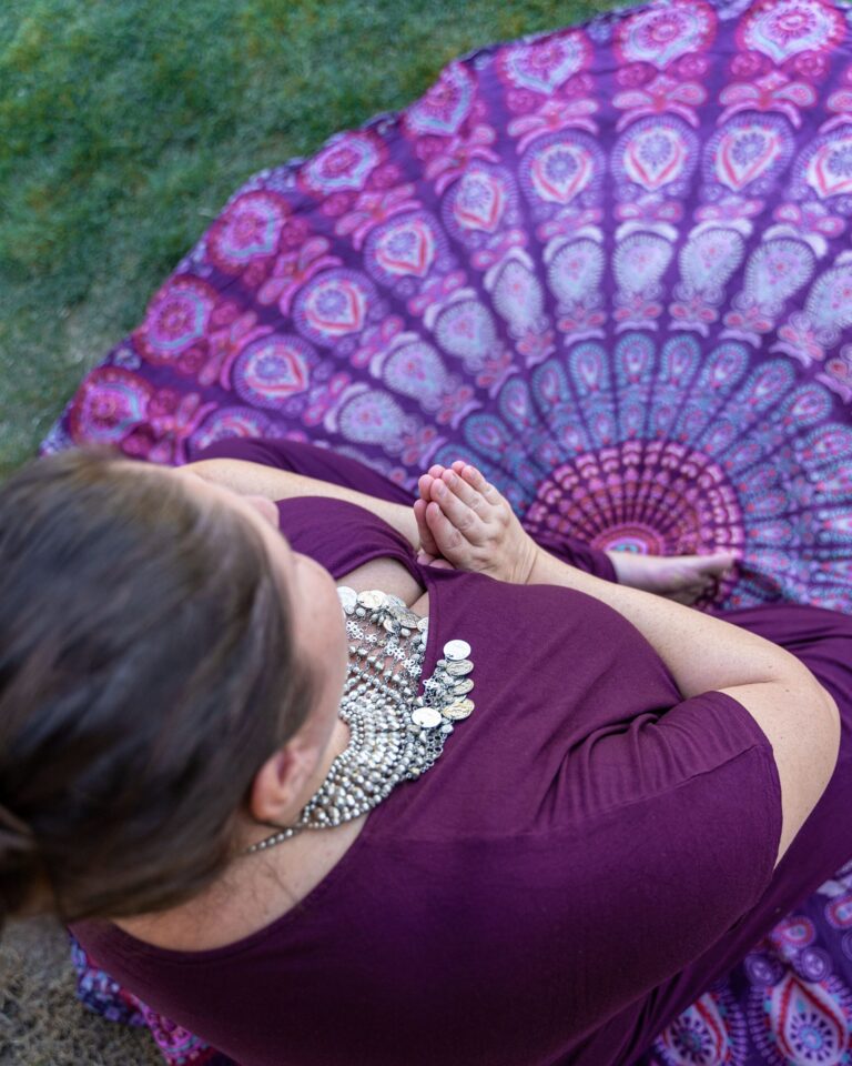 Magnolia, Meditation & Achtsamkeit, Julia Mauroschek - Frau sitzt in Meditationshaltung auf einer Decke im Gras